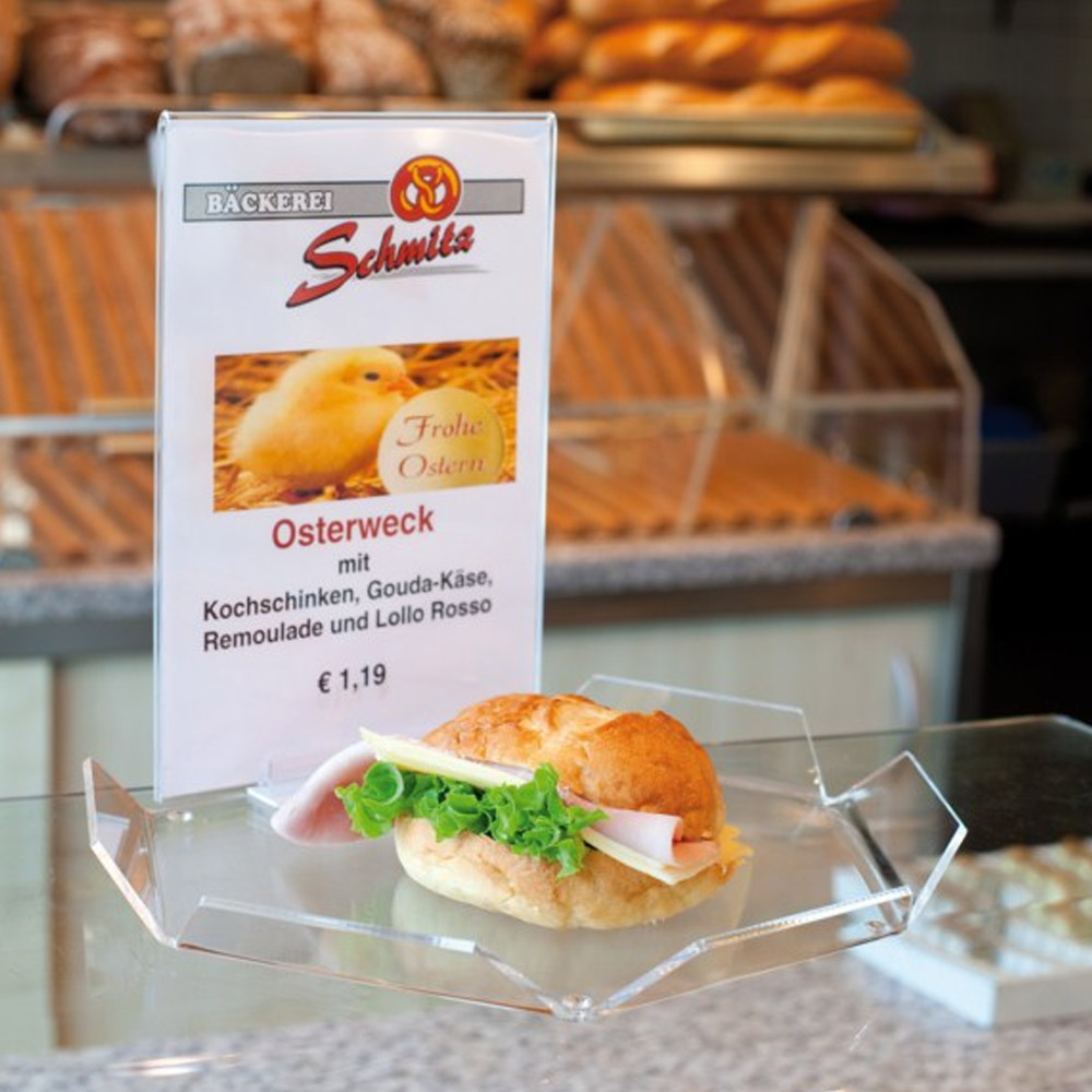 Probier Tablett mit belegtem Brötchen auf einem Tisch und im Hintergrund eine Bäckerei